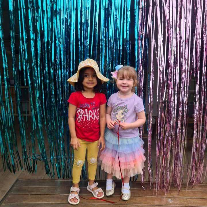 Two girls smiling at the camera with streamers on background - Cannon Hill Your ELC Christmas Celebration