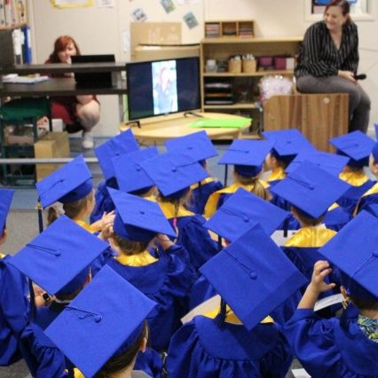 Kids looking at the monitor on their graduation uniforms - Your ELC