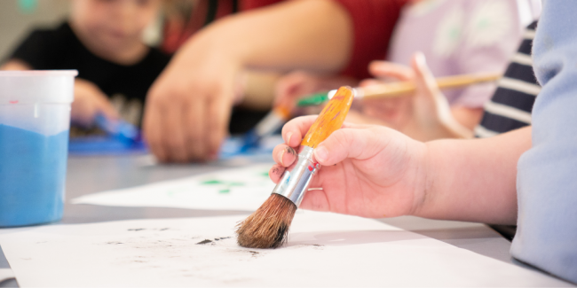Gross Motor Skills A kid's hand holding a paint brush - Your ELC blog image
