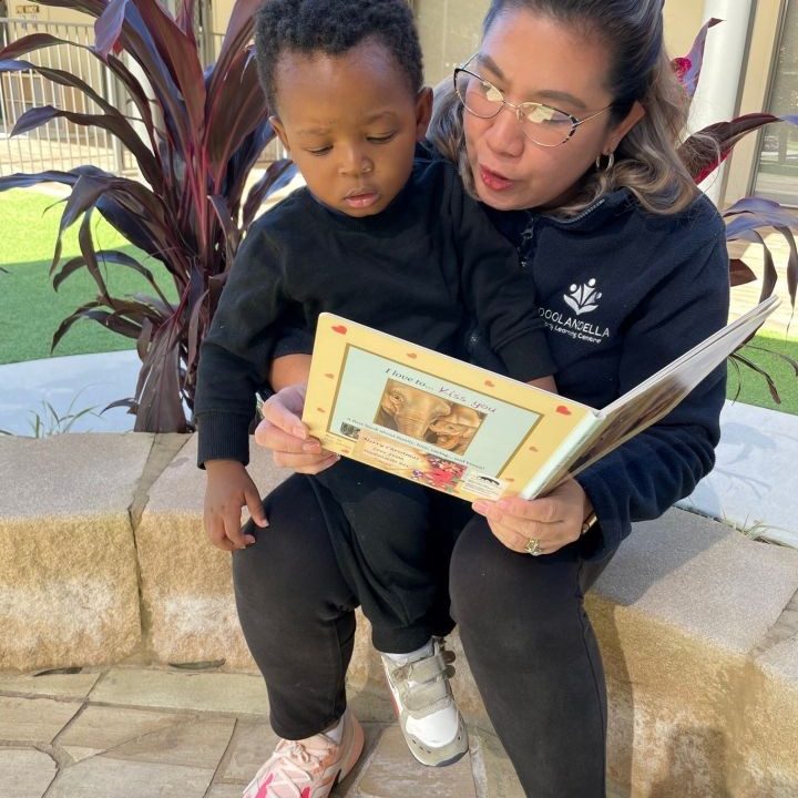 A teacher reading a book to a child - Doolandella Early Learning Centre