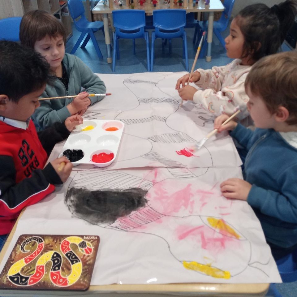 Kids colouring a giant snake on the table - Doolandella July 2022 Newsletter