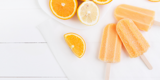 Frozen popsicles Frozen orange pops on a table with sliced oranges - Your ELC blog image
